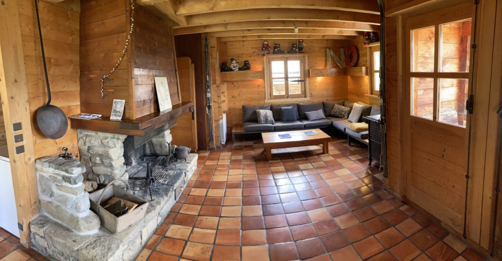Intérieur Chalet du Gran Maci Manigod : salon rénové avec tomette ancienne et cheminée en pierre